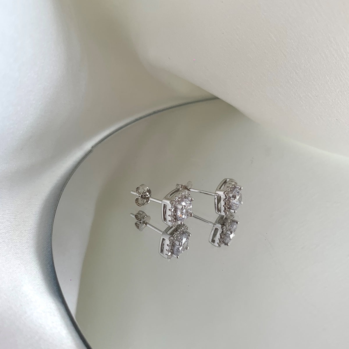 Silver earrings with clear stones on a white surface