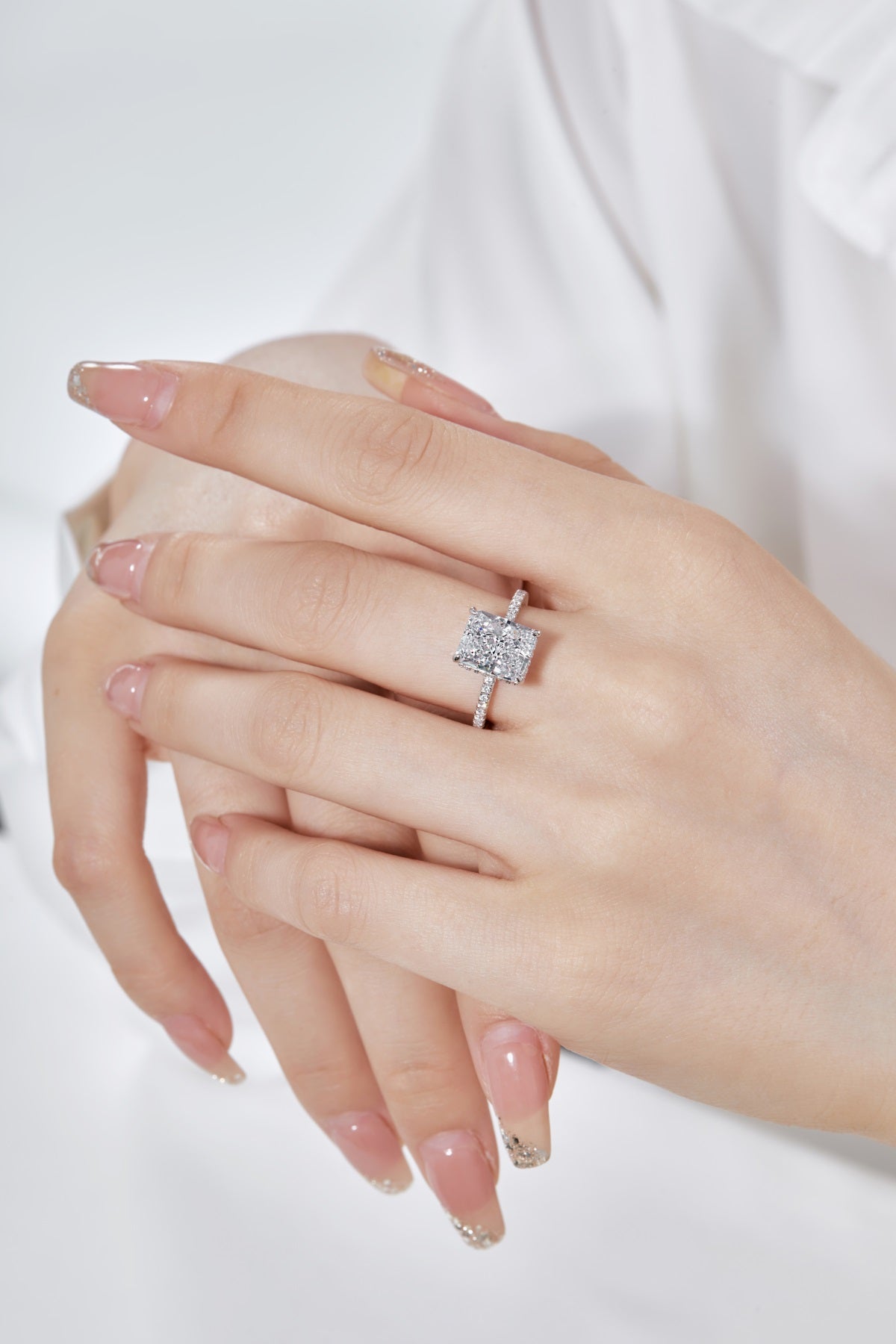 Hand wearing a diamond ring on a white background