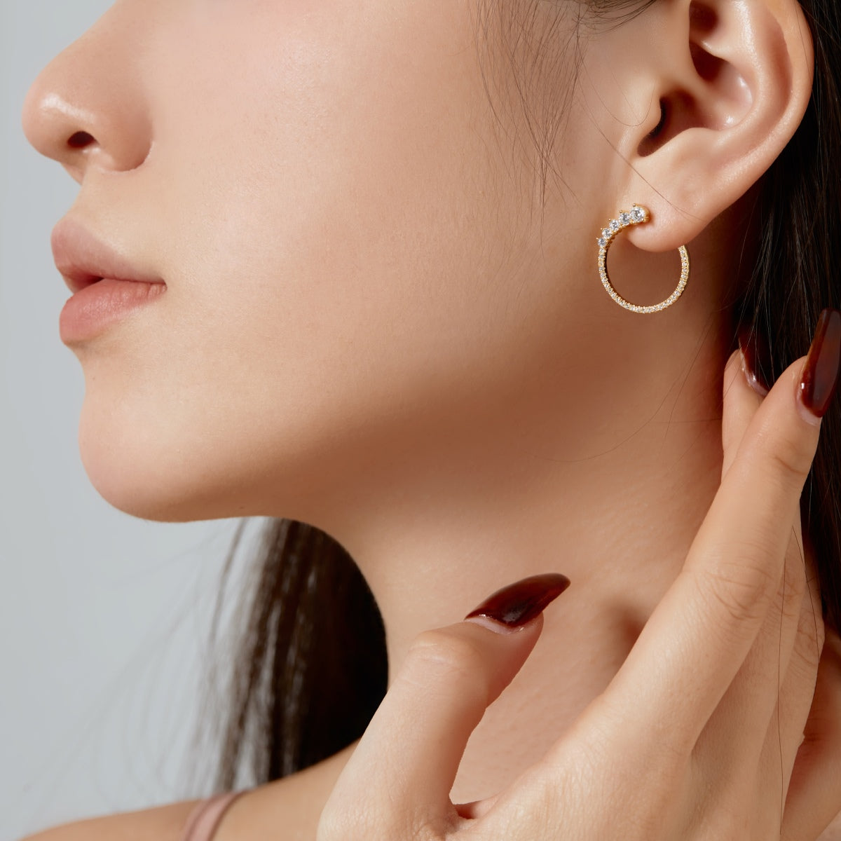 Close-up of a woman wearing a gold hoop earring with diamonds.