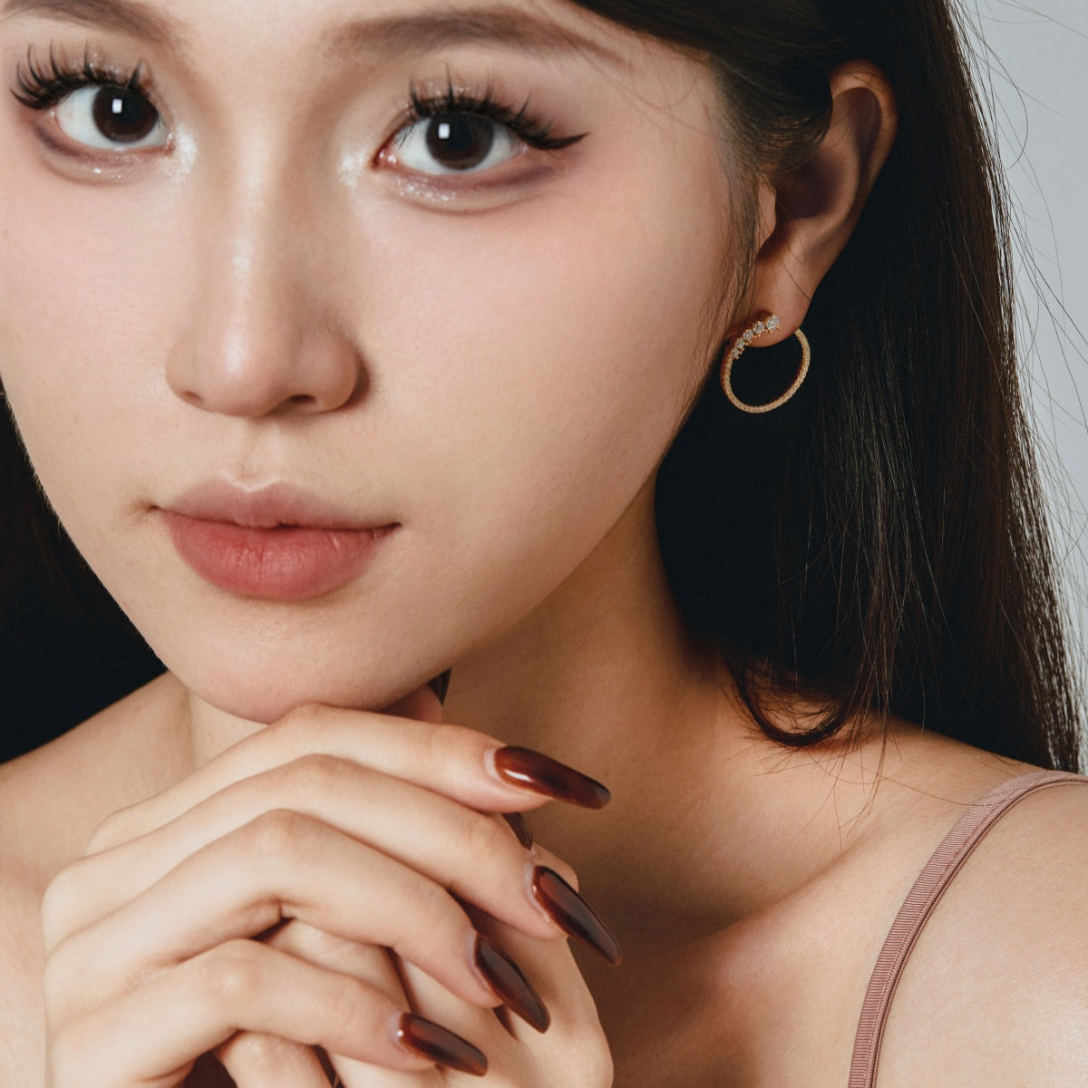 Close-up of a woman wearing hoop earrings with a neutral background