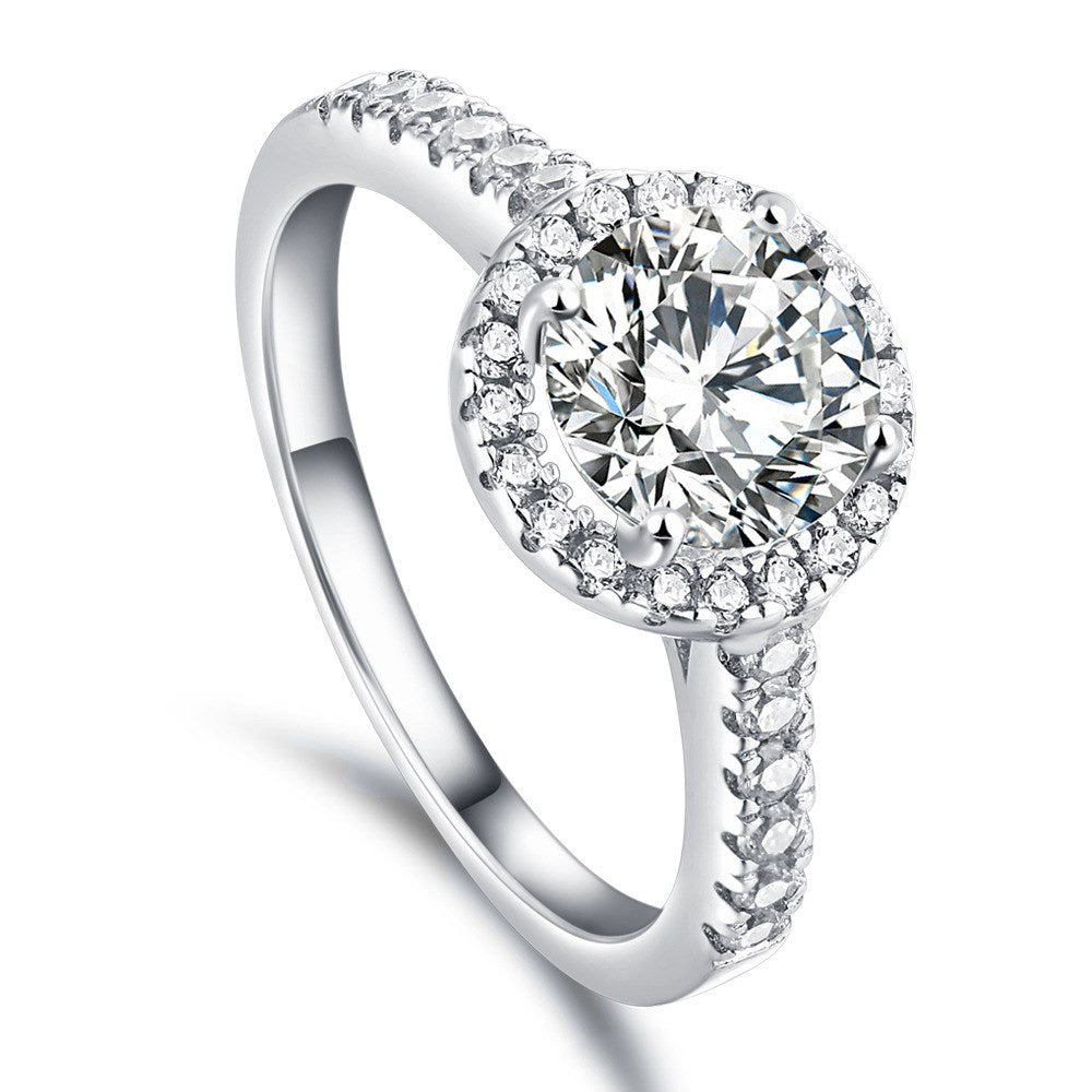 Silver ring with a large diamond and smaller diamonds on the band against a white background